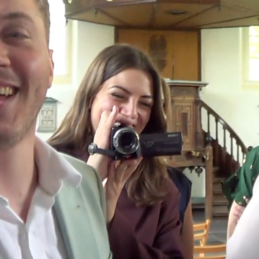Gast filmt lachend met een camcorder tijdens een bruiloft
